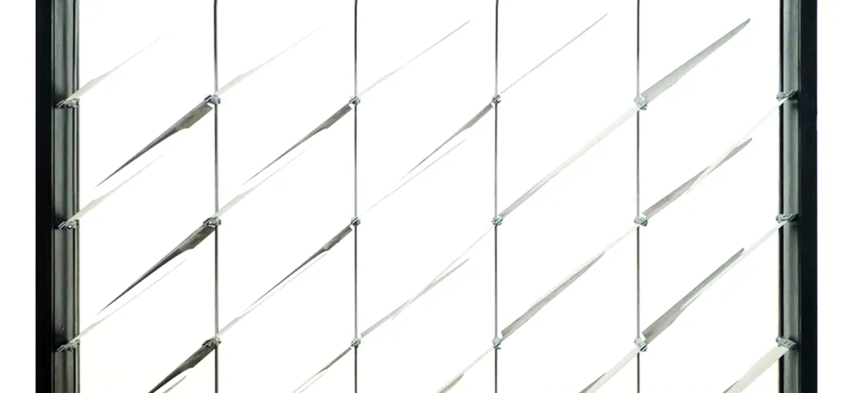 Close-up of a bimetal facade prototype with diagonal fins rotating between glass panels for solar heat mitigation.