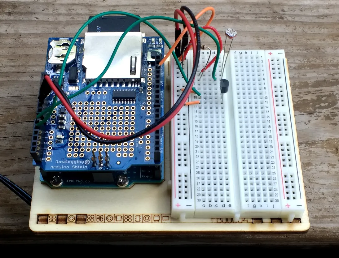 Arduino setup with sensors and breadboard for logging light and temperature data with timestamps.